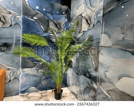 A close-up of a real plant that is present to enhance the look of the specific is in the corner of the living room interior at the show booth, which also has blue colored tiles.