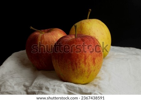 Three apples on a kitchen towel black background