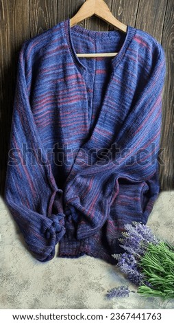 Handmade knitted products. Knitted cardigan made of purple and red threads. Gray background. Copy space Royalty-Free Stock Photo #2367441763