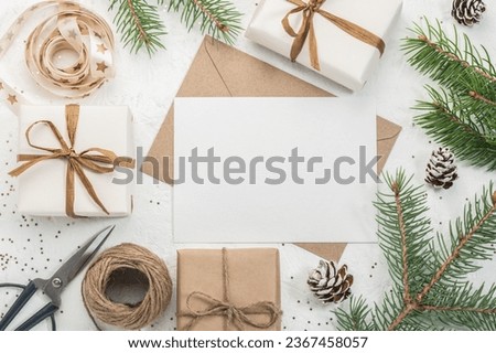 Christmas gift boxes, craft paper envelope and blank form, ribbons and scissors on a white background and fir branches. Christmas greeting card. Boxing Day. Royalty-Free Stock Photo #2367458057