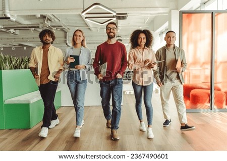 Group of young smiling multiracial business people, colleagues walking in modern office, successful business, career concept. Portrait happy students looking at camera in university campus, education Royalty-Free Stock Photo #2367490601