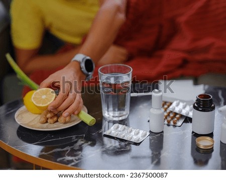 Ginger, lemon, onion and different drugs on table on background sick man. Alternative remedies and traditional pills to treat colds and flu. Natural medicine vs conventional medicine concept Royalty-Free Stock Photo #2367500087
