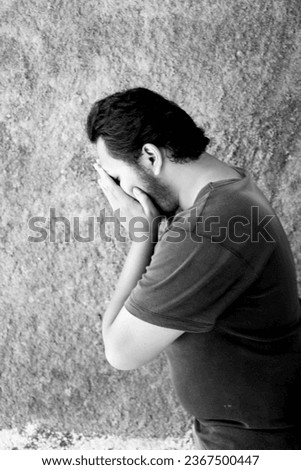 A remorseful man, his face veiled, shrouded in black and white, concealing regret in a monochrome world. Royalty-Free Stock Photo #2367500447