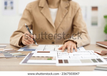Architecture concept, Female architect selecting color and designing house interior in blueprint.