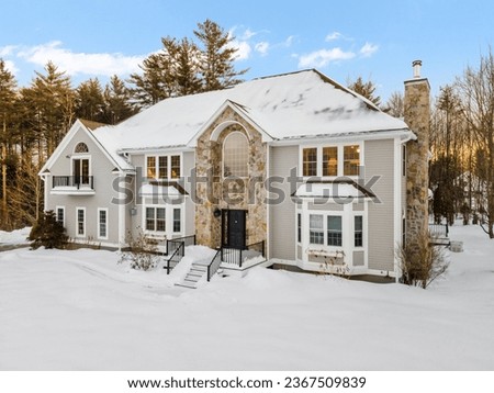 A modern two-story house on snowy winter landscapewith trees in New England Royalty-Free Stock Photo #2367509839
