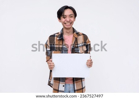 An excited young asian man grinning while holding a blank white signage Isolated on a white background.
