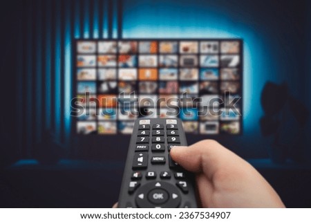 VOD service screen. Man watching TV with remote control in hand. Royalty-Free Stock Photo #2367534907