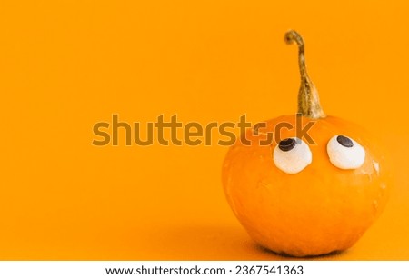 Beautiful jack o lantern pumpkin with eyes on an orange background.Creative halloween concept backdrop.Kids halloween pumpkin craft.