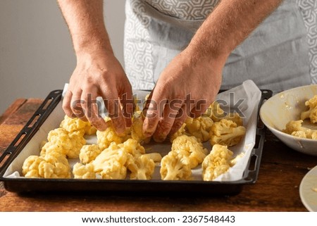 male hands dipping cauliflower into egg in the kitchen