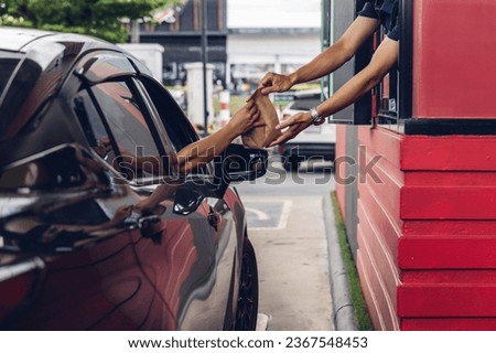 Hand Man in car receiving coffee in drive thru fast food restaurant. Staff serving takeaway order for driver in delivery window. Drive through and takeaway for buy fast food for protect covid19. Royalty-Free Stock Photo #2367548453
