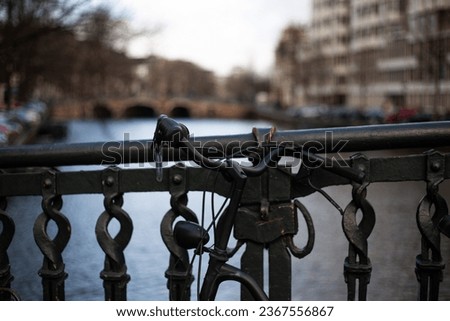 bicycle leaning on the railing of the bridge with the canal in the background, photo taken in Amsterdam, Holland