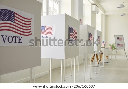 Interior of an empty polling place in the US. Row of empty white voting booths with American flags at the ballot station. Elections in the USA, democracy concept 