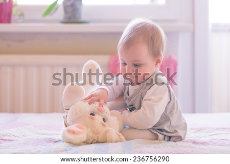 10 months old baby girl playing with a plush bunny Royalty-Free Stock Photo #236756290