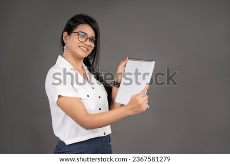 Beautiful woman holding a white board sheet on a grey background