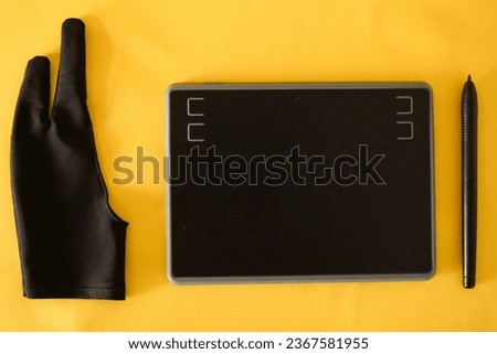 Electronic drawing pen tablet , stylus and glove isolated yellow Royalty-Free Stock Photo #2367581955