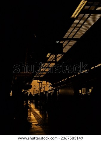 A vertical shot of dark railway station with silhouettes of people at night