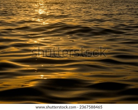 abstract waves forming on the sea at sunset ,yellow black sunset background. High quality photo