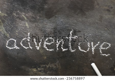 The word adventure written with chalk on black stone.