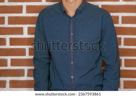 Men's business style clothing skinny guy fashion in blue shirt on brick wall background.