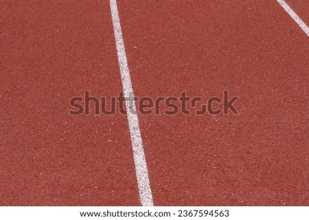 A high-resolution close-up of a track and field running surface featuring multiple lanes is presented in this stock photo