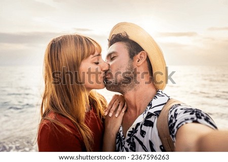 Young couple in love kissing at the sunset beach - Romantic boyfriend and girlfriend enjoying summer vacation together