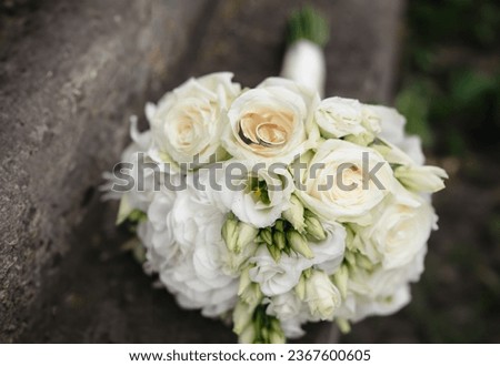 Two wedding rings on bouquet of roses flowers.