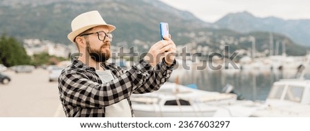 Traveller millennial man taking pictures of luxury yachts marine during sunny day - travel and summer banner with copy space