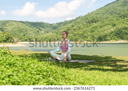 portrait of yoga girl sitting on bay shore in lotus pose, meditating. photo captures her in bright sunlight, wearing yoga costume, representing healthy lifestyle, spiritual practices, inner calmness