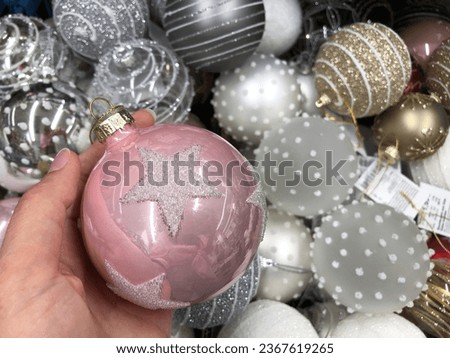hand holding a pink christmas bauble ornament at store or xmas market