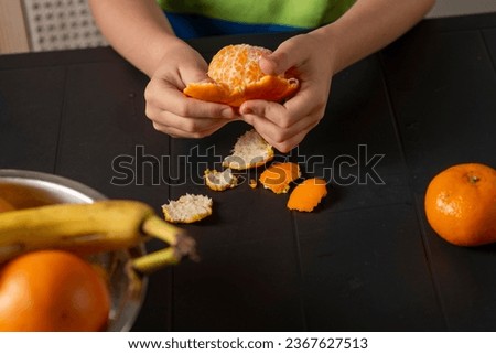 children's hands peel a tangerine over the table