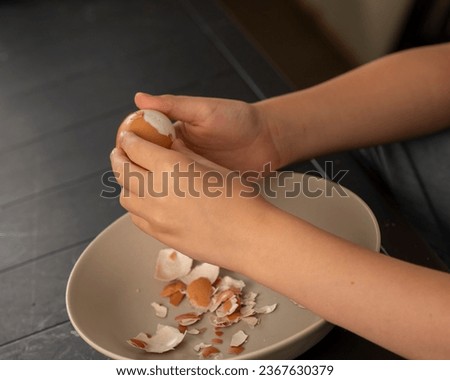 children's hands peeling a boiled egg in the kitchen natural shot
