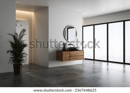 Bright bathroom interior with white tones wall, concrete floor, wooden vanity with black sink and oval mirror, white bathtub, panoramic windows. Royalty-Free Stock Photo #2367648625