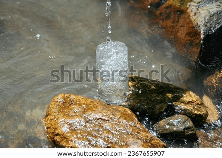 A glass filled with water on a rock