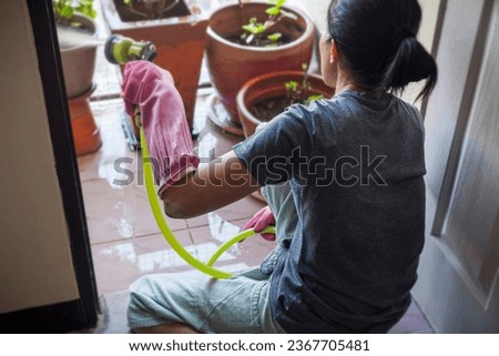 Picture of a woman watering plants on the balcony of a house