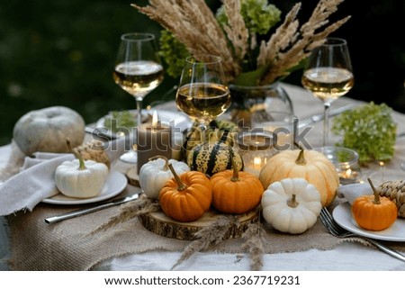 Fall table decoration with pumpkins, wine. Family thanksgiving dinner arrangement outdoors in the garden. Countryside style, simple handmade setting, autumn mood