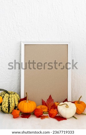 Mock up template white portrait frame with fall branches and pumpkin decor on wooden background against the wall. Autumn concept with copy space for text