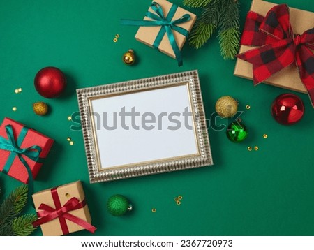 Christmas and New Year picture frame mock up with gift box and decorations on green background. Top view, flat lay