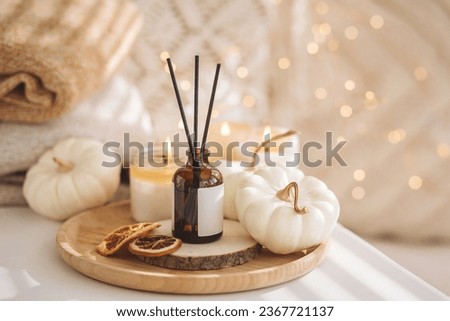 Home comfort, coziness, aromatherapy. Cozy fall interior with knitted wool warm sweater, burning candles and autumn aroma perfume diffuser in the bedroom. Pumpkin pie, cinnamon, anise Royalty-Free Stock Photo #2367721137