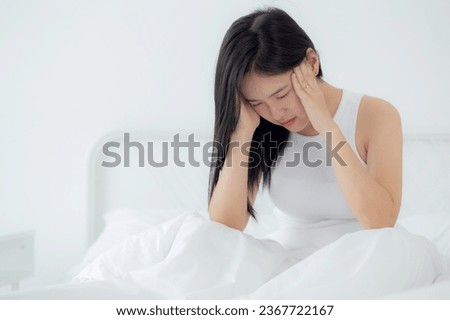 Young asian woman sitting on bed pain headache in the bedroom at home, unhappy female exhaustion and sick headache, anxiety and unwell, dizziness and disorder, medical and health concept. Royalty-Free Stock Photo #2367722167
