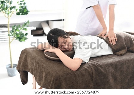Young Asian woman receiving a massage (manipulative treatment) in bed from a female chiropractor
 Royalty-Free Stock Photo #2367724879