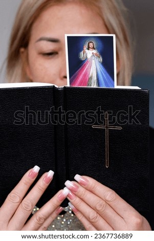 Catholic woman reading the bible with an image of Jesus. Faith concept. 