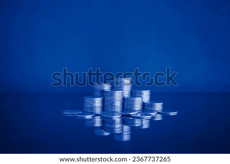 Pile of money coin on blue background with copy space. Business and financial concept with blue color filter. 