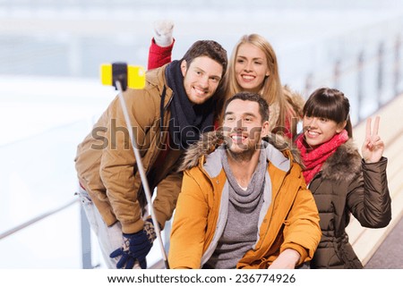people, friendship, technology and leisure concept - happy friends taking picture with smartphone selfie stick on skating rink Royalty-Free Stock Photo #236774926