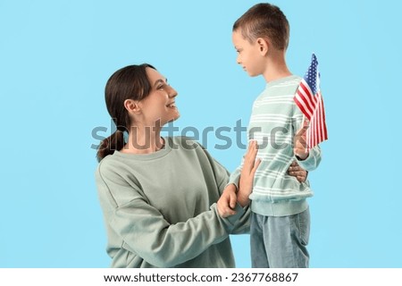 Little boy with USA flag and his mother on blue background. Veterans Day celebration