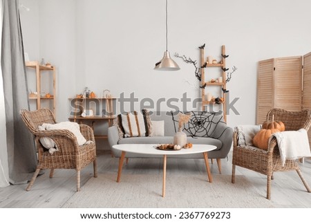 Interior of light living room decorated for Halloween with sofa and armchairs