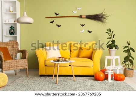 Interior of living room decorated for Halloween with yellow sofa and armchair