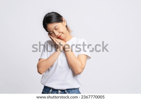Tired Asian woman wearing a white t-shirt is napping alone on a white background.