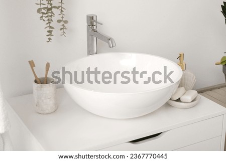 Sink bowl and cup with toothbrushes on chest of drawers in bathroom, closeup Royalty-Free Stock Photo #2367770445