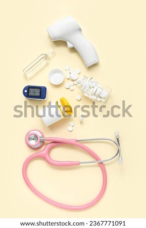 Stethoscope, pills, pulse oximeter, infrared thermometer and ampule on yellow background Royalty-Free Stock Photo #2367771091