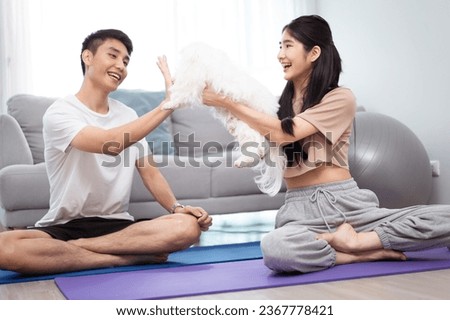 Happy lovely Asian young couple with a Maltese dog doing a yoga or stretching exercise together. Joyful Asian young couple with Maltese dog lying down on exercise mat.